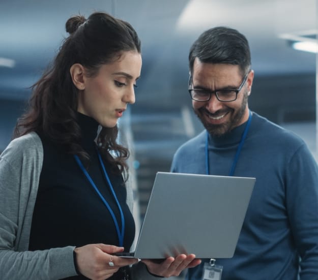 Woman and man looking at a laptop together in an office hallway