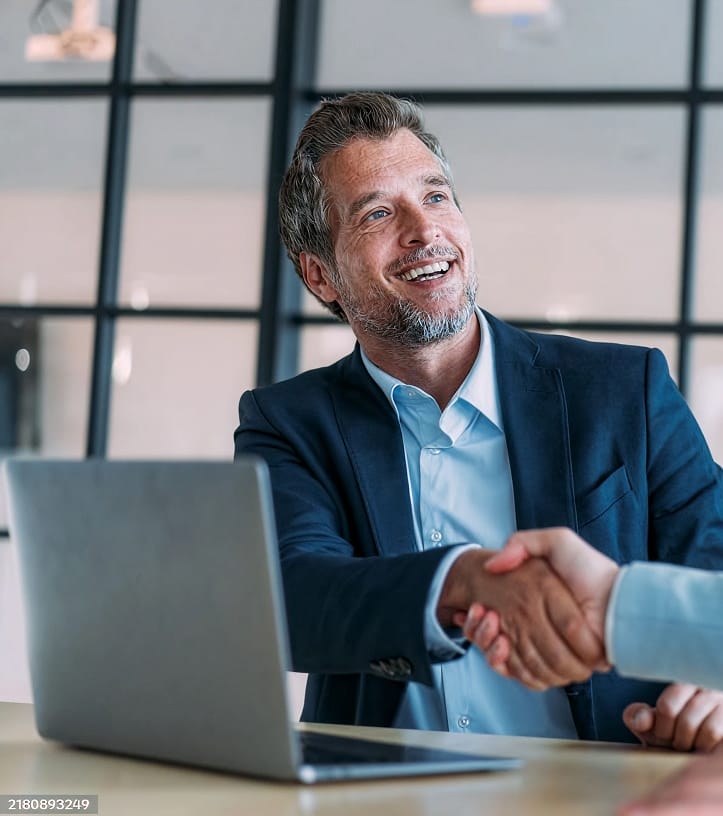 Smiling businessman shaking hands with a partner in an office setting